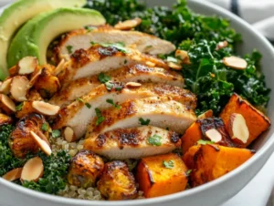 Colorful chicken protein bowl with quinoa, sweet potatoes, kale, and sliced chicken, garnished with almonds